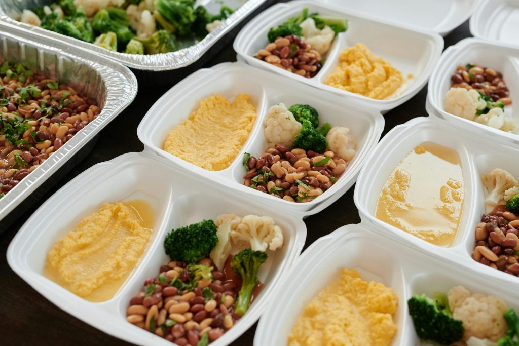 Assorted meal prep containers with beans, broccoli, and mashed potatoes, perfect for healthy eating.